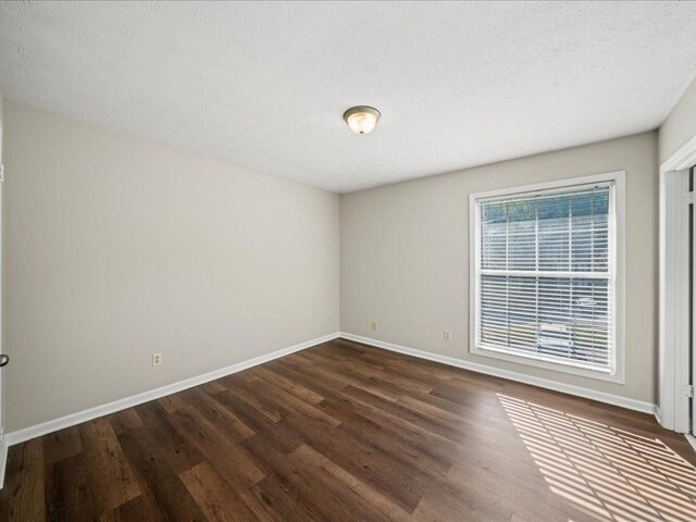 spare room with a textured ceiling and dark wood-type flooring