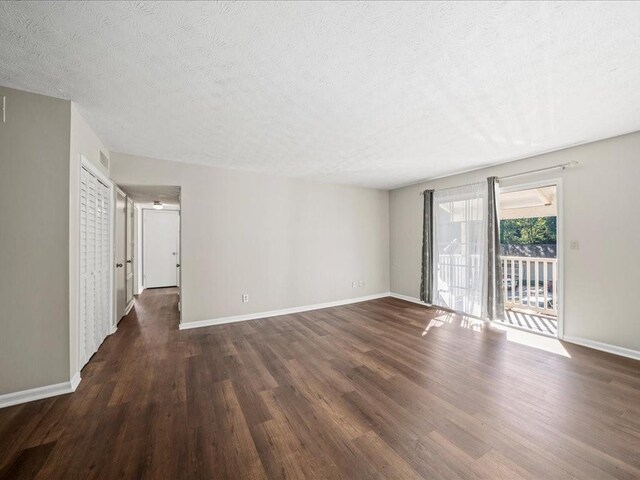 unfurnished room with a textured ceiling and dark wood-type flooring