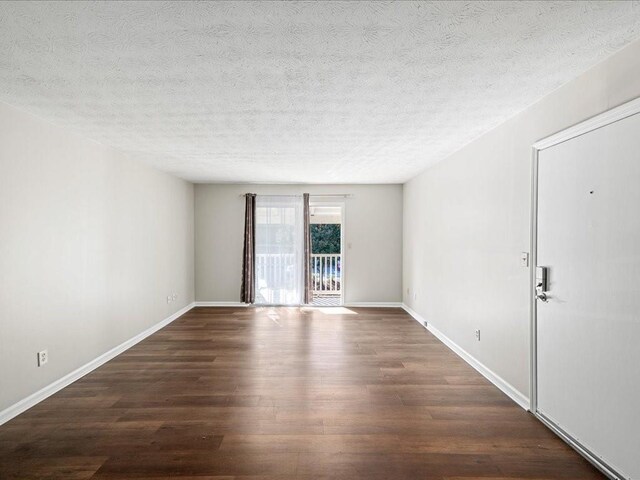 empty room with a textured ceiling and dark hardwood / wood-style floors