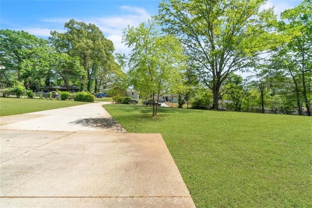 view of community with a lawn and concrete driveway
