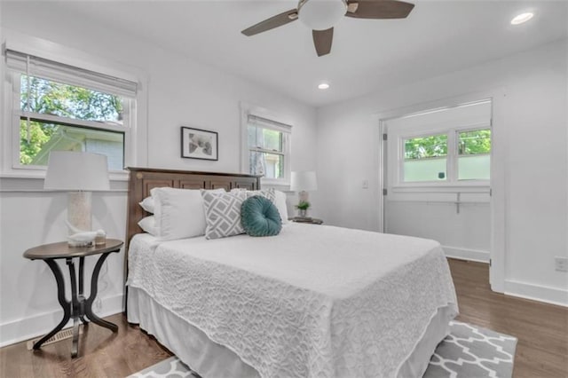 bedroom with baseboards, multiple windows, and wood finished floors