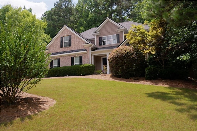 view of front facade with brick siding and a front yard