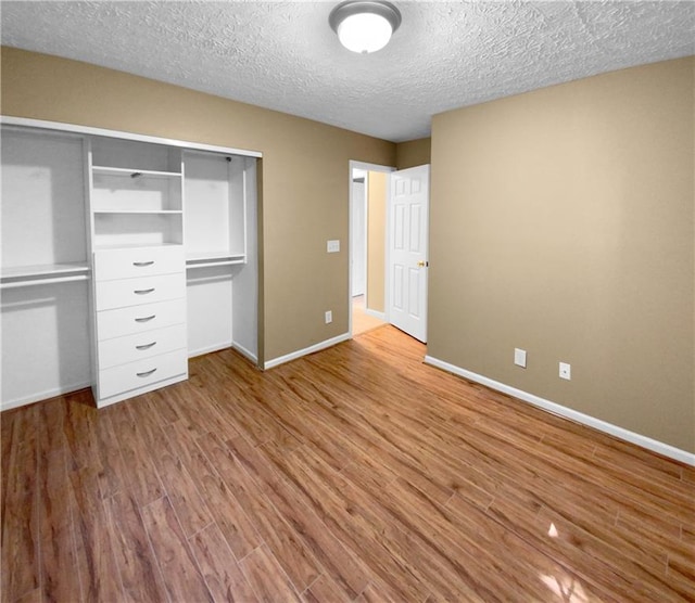 unfurnished bedroom with light wood-type flooring, a closet, and a textured ceiling