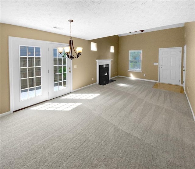 unfurnished living room with light colored carpet, a notable chandelier, and a textured ceiling