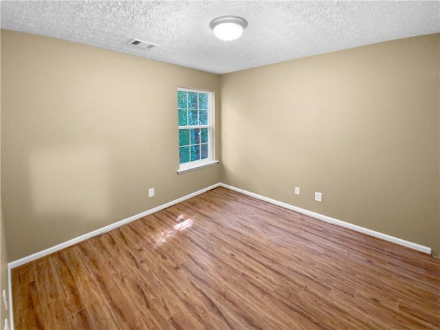 empty room with a textured ceiling and wood-type flooring