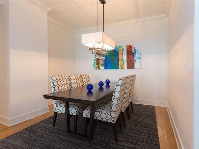 dining space featuring baseboards, a chandelier, wood finished floors, and crown molding