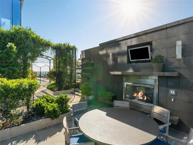 view of patio / terrace featuring outdoor dining area and a glass covered fireplace