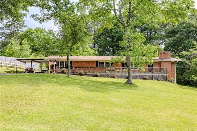 back of property with brick siding, a chimney, a lawn, and an attached carport