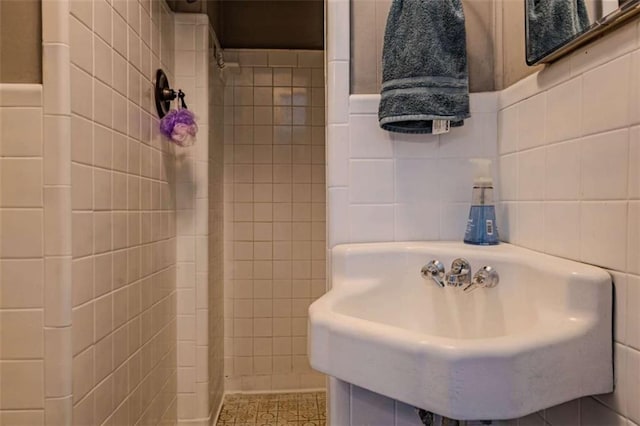 full bath with a sink, tile walls, and tiled shower