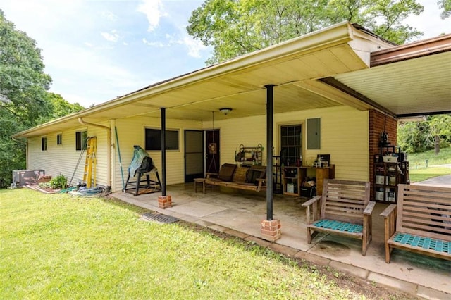 back of house featuring electric panel, a patio area, and a lawn
