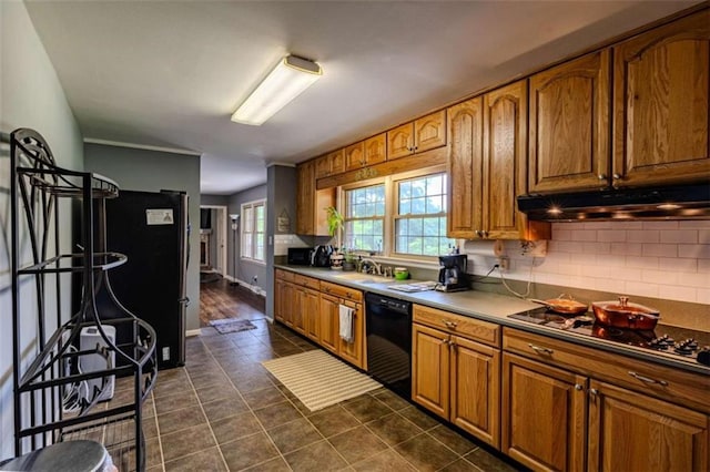 kitchen featuring black appliances, brown cabinets, dark tile patterned flooring, and under cabinet range hood