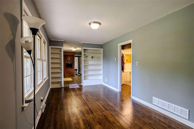 unfurnished room with visible vents, wood finished floors, and baseboards