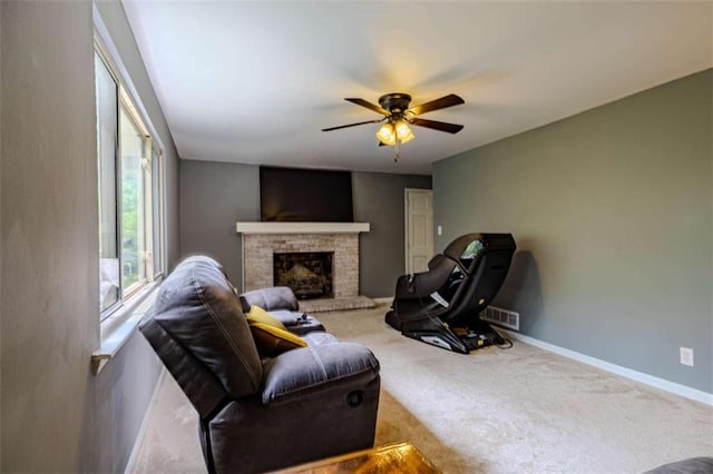 carpeted living area with a brick fireplace, baseboards, a ceiling fan, and visible vents