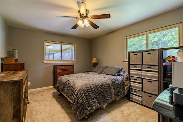 bedroom featuring ceiling fan, light carpet, and baseboards