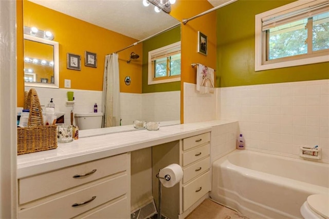 full bath with toilet, tile walls, a shower with curtain, vanity, and a tub