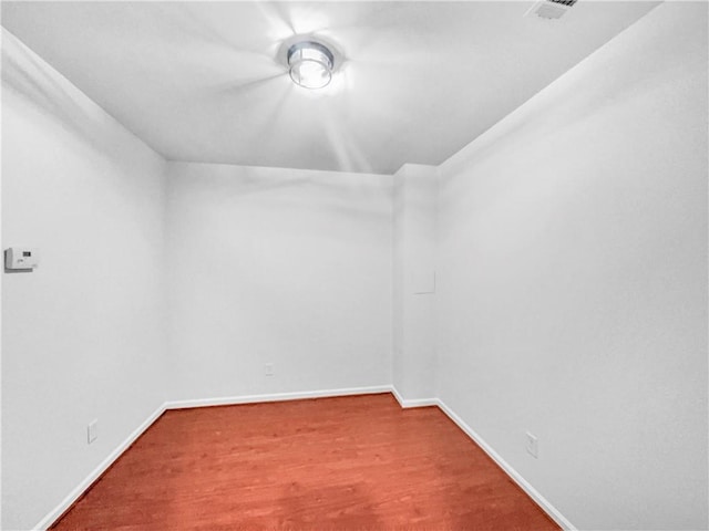 unfurnished room featuring visible vents, wood finished floors, and baseboards