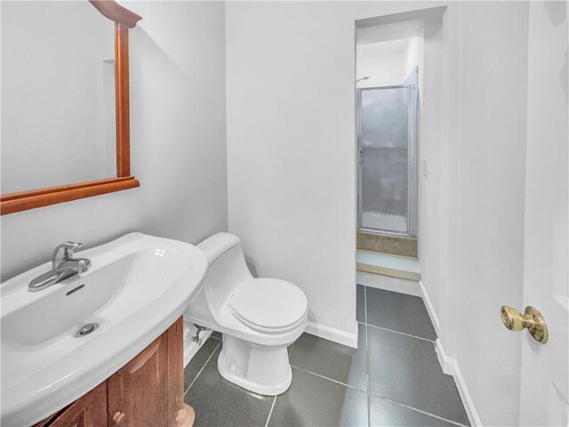 half bath with tile patterned floors, baseboards, toilet, and vanity