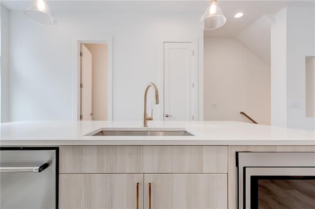 kitchen featuring wine cooler, light brown cabinetry, sink, and hanging light fixtures