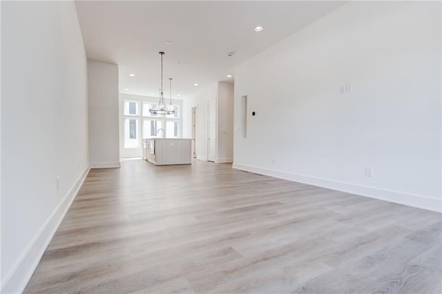 unfurnished living room with a chandelier and light hardwood / wood-style floors