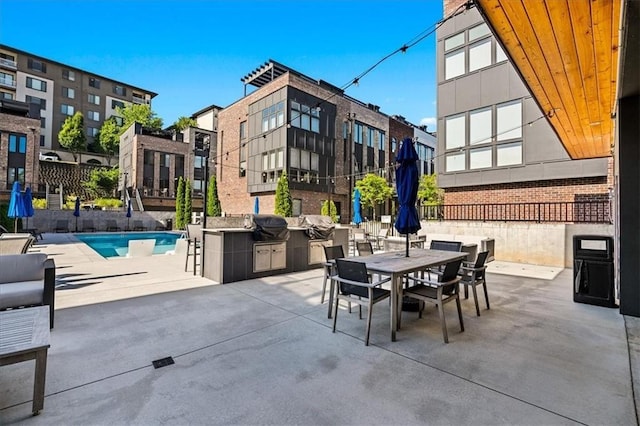 view of patio featuring area for grilling, a community pool, and exterior kitchen