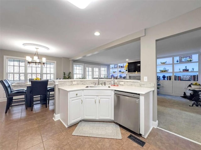 kitchen featuring sink, hanging light fixtures, light tile patterned floors, stainless steel dishwasher, and white cabinets