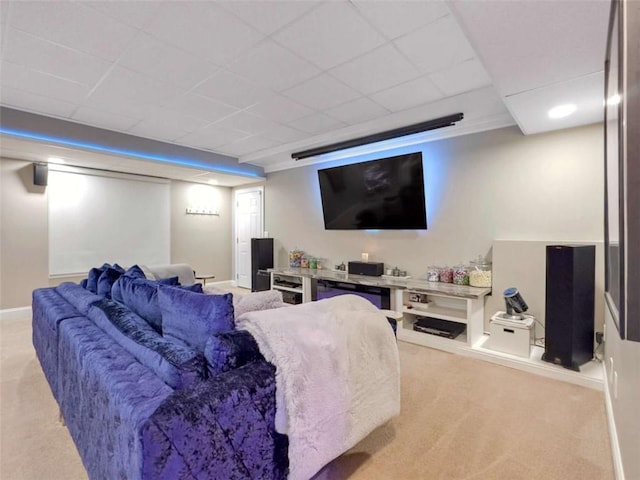 home theater room with a paneled ceiling and light carpet