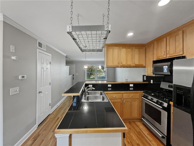 kitchen with sink, stainless steel appliances, light hardwood / wood-style floors, ornamental molding, and tile countertops