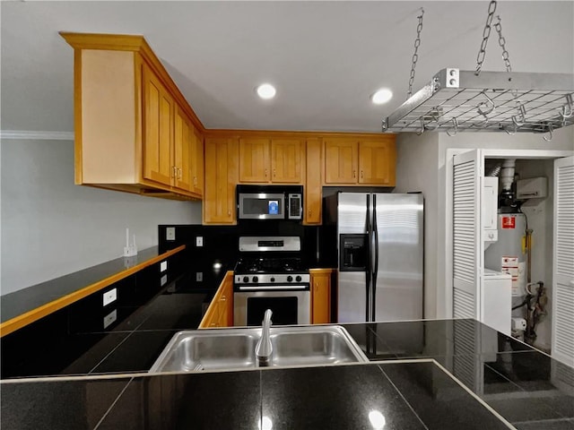 kitchen featuring tile countertops, decorative light fixtures, water heater, sink, and stainless steel appliances