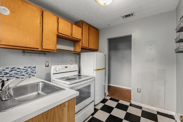 kitchen featuring white appliances, sink, a textured ceiling, and backsplash