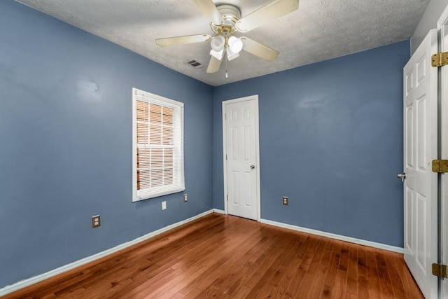 unfurnished bedroom featuring ceiling fan, wood-type flooring, and a textured ceiling