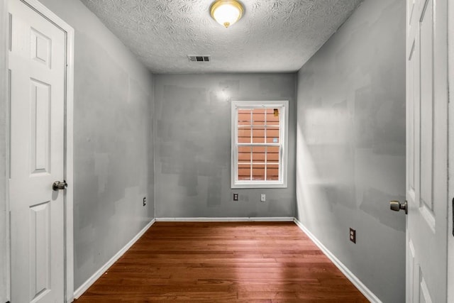 unfurnished room with hardwood / wood-style floors and a textured ceiling