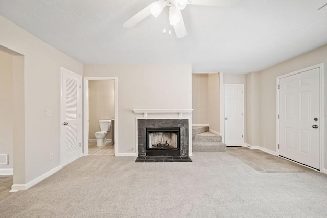 unfurnished living room with carpet floors, visible vents, a tiled fireplace, ceiling fan, and baseboards