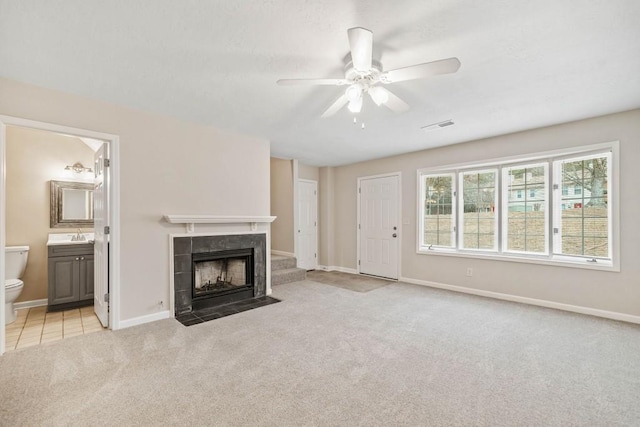 unfurnished living room featuring light carpet, a fireplace, baseboards, and a ceiling fan