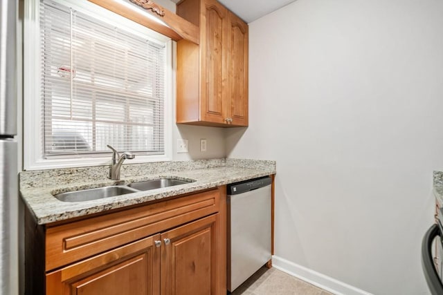 kitchen featuring a sink, baseboards, light stone counters, and stainless steel dishwasher