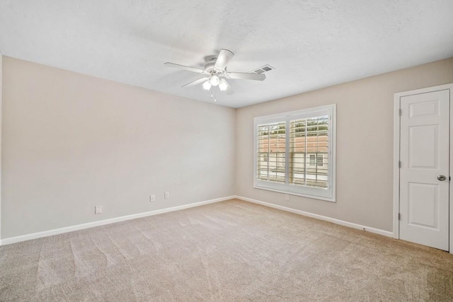 carpeted empty room with a textured ceiling, visible vents, a ceiling fan, and baseboards