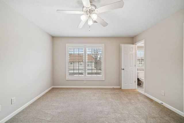 carpeted empty room with ceiling fan and baseboards