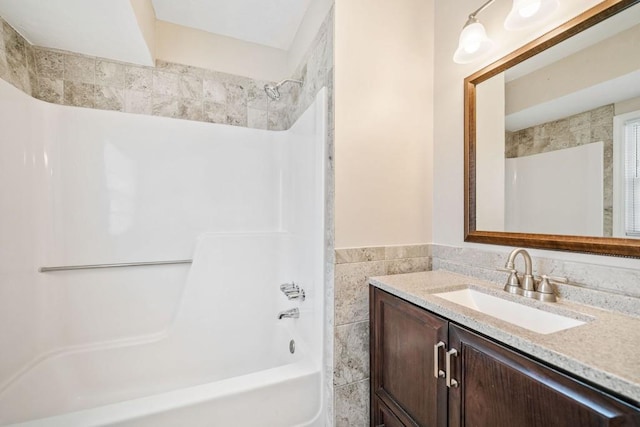 full bath with shower / bathing tub combination, tile walls, and vanity