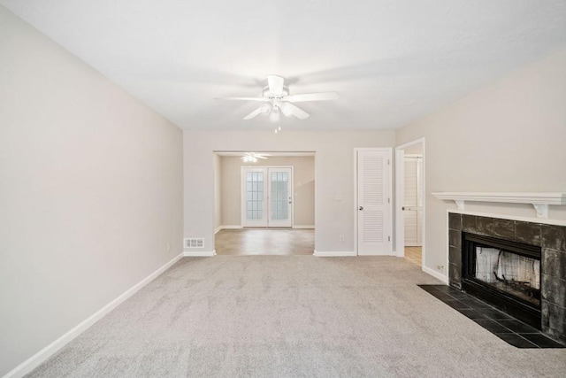 unfurnished living room featuring ceiling fan, carpet flooring, visible vents, baseboards, and a tiled fireplace