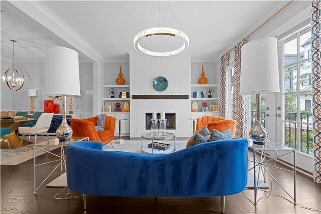 living area with built in features, a large fireplace, a healthy amount of sunlight, and ornamental molding