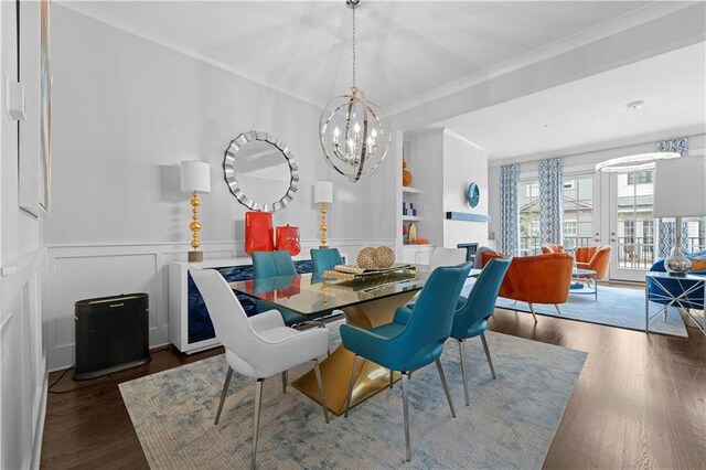 dining space with a chandelier, a decorative wall, dark wood finished floors, and crown molding