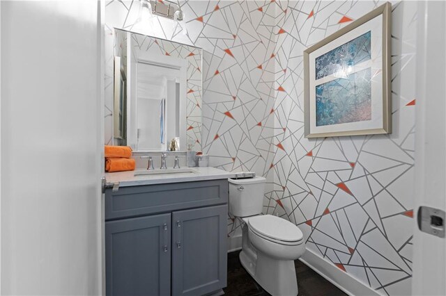 bathroom featuring toilet, vanity, and tile walls