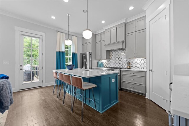 kitchen with pendant lighting, a breakfast bar area, gray cabinets, light countertops, and an island with sink