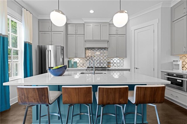 kitchen with stainless steel appliances, a kitchen island with sink, and light countertops