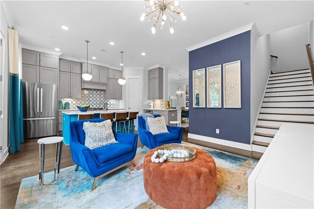 living room with a notable chandelier, recessed lighting, wood finished floors, baseboards, and stairs