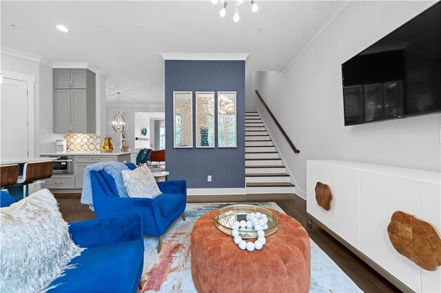 living area with stairway, a chandelier, dark wood-type flooring, and crown molding