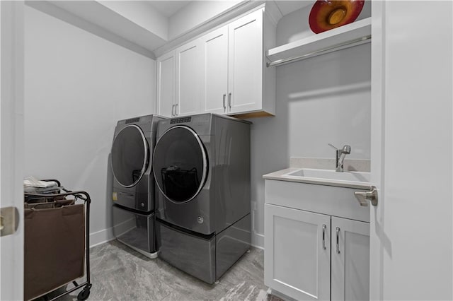 laundry room featuring washer and dryer, cabinet space, a sink, and baseboards