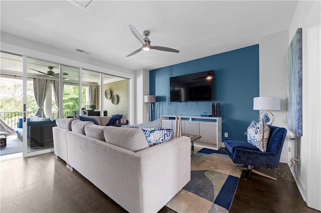 living area featuring ceiling fan, visible vents, dark wood finished floors, and baseboards