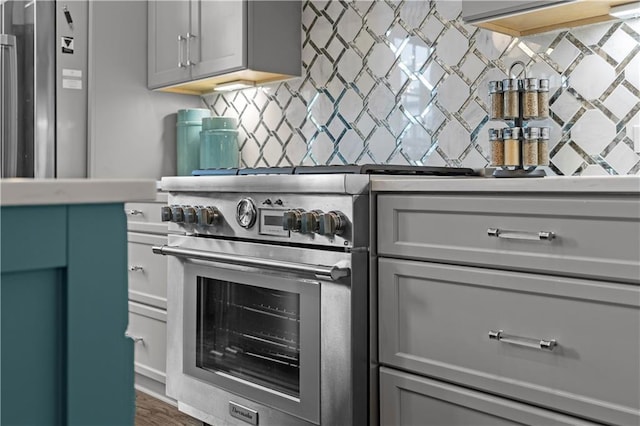 kitchen with stainless steel range, decorative backsplash, light countertops, and gray cabinetry