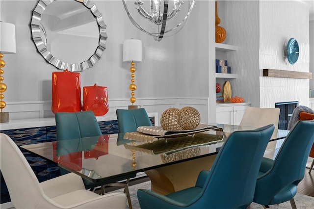 dining area with built in shelves, a fireplace, and an inviting chandelier