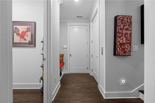 hallway featuring dark wood-style floors, visible vents, and baseboards